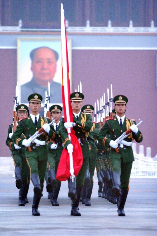 pla soldiers are marching in front of tiananmen square for a national flag raising ceremony