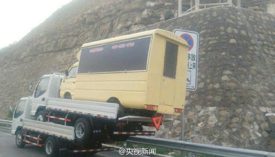 A small truck is carring two other trucks of the same size on a freeway in shanxi
