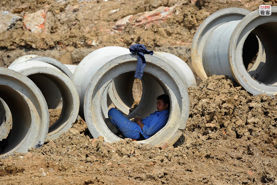 A worker is sleeping in a big concrete tube on construction site